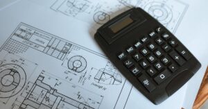 Close-up of a calculator resting on technical engineering blueprints, showcasing precise calculations.